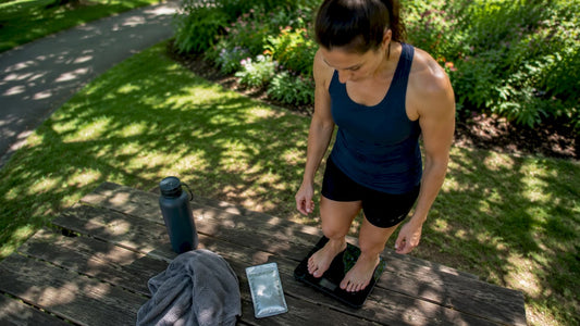 Female athlete weighing herself pre-workout outdoors