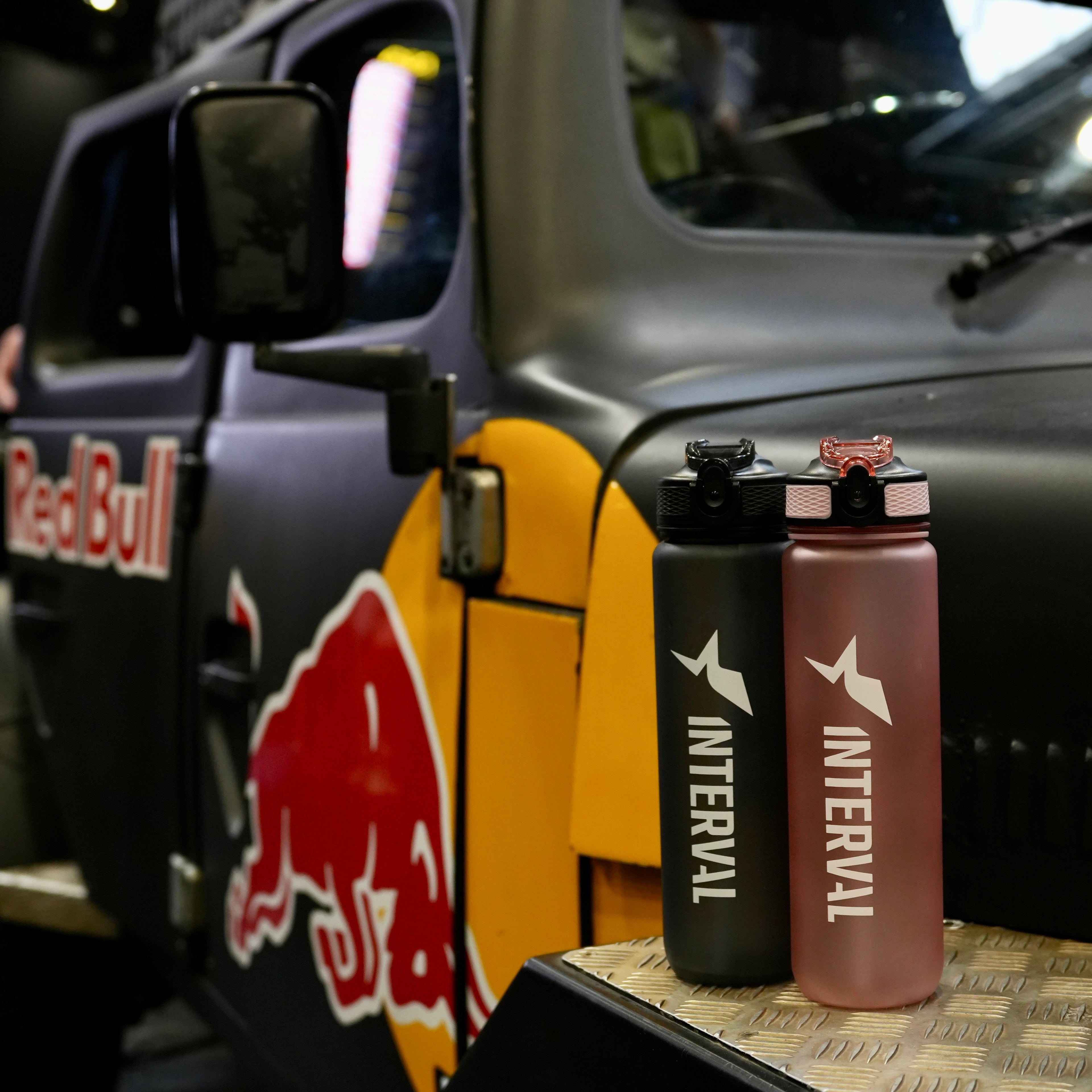 Interval water bottles on a car dashboard with Red Bull branding in the background