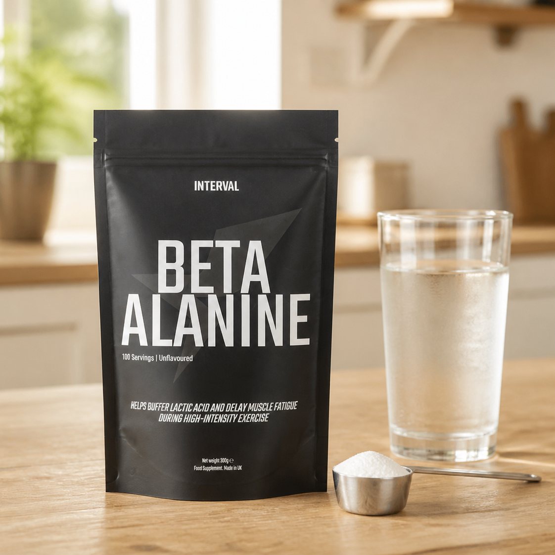 A black stand-up pouch of INTERVAL Beta Alanine powder stands on a wooden countertop, with a glass of water and a small metal scoop of white powder beside it. The background shows a softly blurred kitchen interior.
