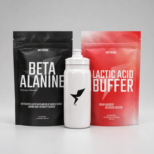 Three fitness products arranged on a light gray studio background: a black stand-up pouch labeled INTERVAL BETA ALANINE, a white bottle with a black bird logo, and a red stand-up pouch labeled INTERVAL LACTIC ACID BUFFER.